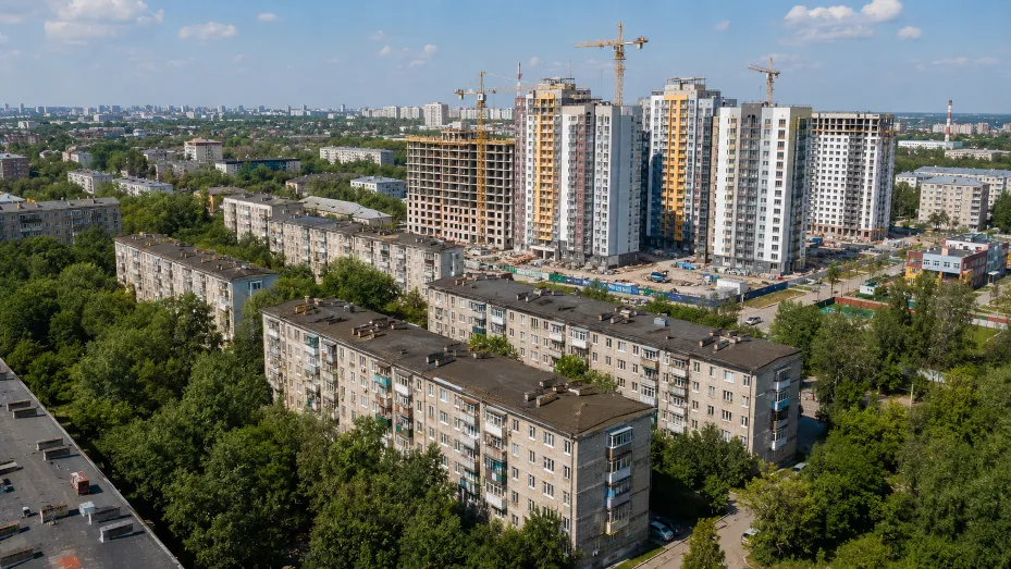 Аэросъёмка российского города: на переднем плане старые пятиэтажки, за ними — строящийся жилой комплекс с башенными кранами